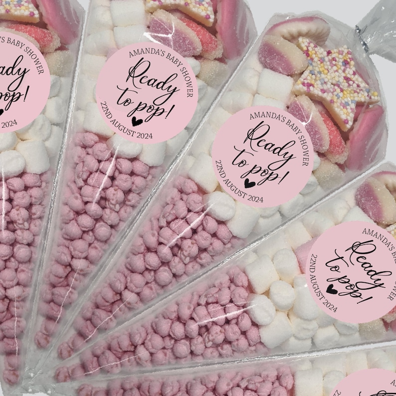 May include: Pink and white candy filled cone party favors with a pink circle sticker that says "Ready to pop!" with the date "22nd August 2024" printed on it.