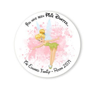 May include: A round door hanger with a pink and white watercolour background. Tinkerbell is flying in the centre of the circle. The text "You have been Pixie Dusted... The Edward Family - Room 2571" is written around the edge of the circle.