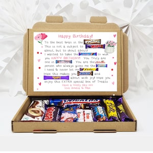 May include: A brown cardboard gift box filled with assorted chocolate bars. The inside lid features a printed message for a birthday, incorporating small images of candy bars like Galaxy, Wispa, Millions, Kinder, Boost, Flake, Snickers, and Twirl.