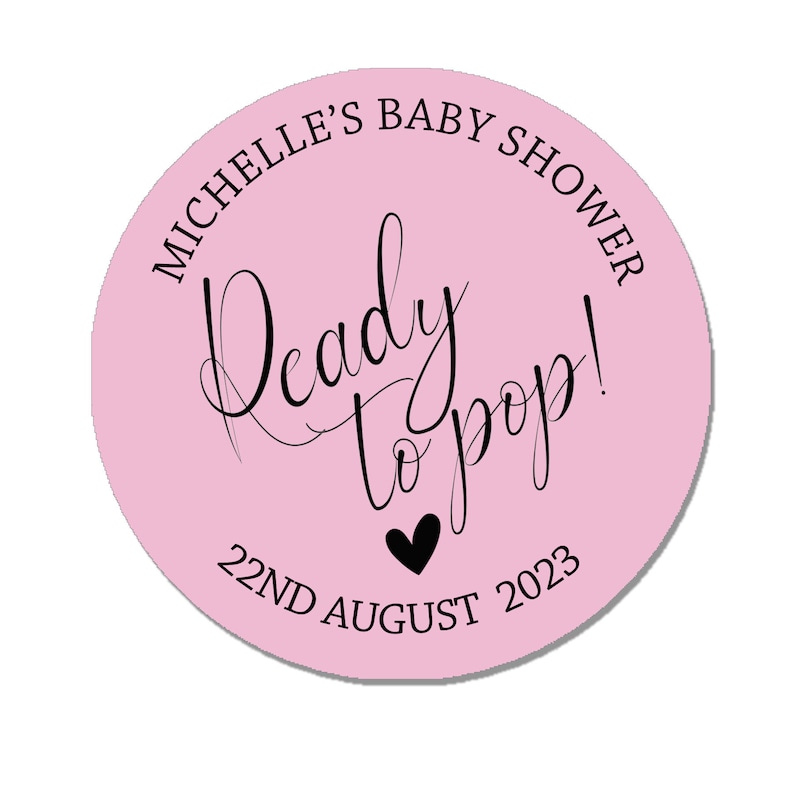 May include: Pink round sticker with black text that says "Michelle's Baby Shower Ready to Pop! 22nd August 2023".