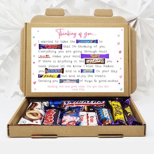 May include: A brown cardboard box with the lid open, revealing a selection of chocolate bars. Inside the box is a handwritten note that reads "Thinking of you... I wanted to take the... to... that I'm thinking of you. Everything you are going through must... make your mind... If there is anything in the... you need, please let me know. I hope this makes you... and is a... to your day... out and enjoy the treats. Sending you... of hugs & good wishes. Sending love and good vibes You got this Girl Love Ellie"