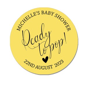 May include: Yellow circle sticker with black text that reads "Michelle's Baby Shower Ready to Pop! 22nd August 2023".