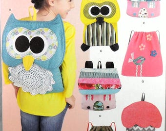 May include: A sewing pattern for making six different backpacks. The patterns include a pink house, a green tree, a pink bird, a yellow owl, a blue owl, and a gray and pink mushroom. The pattern is from The Sewing Loft.