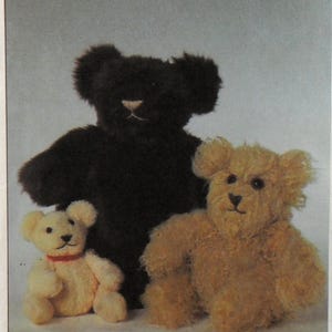May include: Three plush teddy bears of varying sizes and colors. The largest bear is dark brown, the middle bear is light brown, and the smallest bear is cream-colored with a red collar. All bears have black eyes and noses.