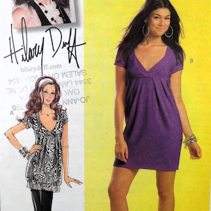 May include: McCall's sewing pattern showing a purple V-neck dress. The image includes a photo of Hilary Duff and a drawing of a woman wearing a zebra print top and black leggings. The text "Hilary Duff" is visible.
