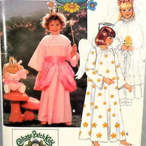 May include: A vintage sewing pattern featuring children's costumes. The costumes include a pink princess dress with a crown and wand, an angel dress with gold stars, and a white wedding dress with a veil. The Cabbage Patch Kids logo is visible.