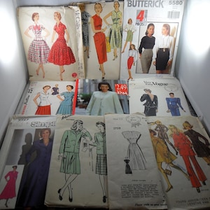 May include: A collection of vintage sewing patterns featuring various garment illustrations including dresses, skirts, jackets, and coats. The envelopes display brand names like Butterick 5580, McCall's, and Vogue, with printed text, prices, and model sketches.