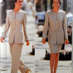 Puede incluir: Traje de dos piezas gris claro con cuello con solapas y cierre de botones. El traje se muestra con pantalón y falda. La chaqueta tiene un corte entallado y el pantalón tiene una pernera ancha. La falda es hasta la rodilla.