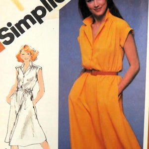 May include: Simplicity sewing pattern showing a woman in a yellow dress with a belt and pockets. The pattern also includes a sketch of a white dress. The word "Simplicity" is visible.