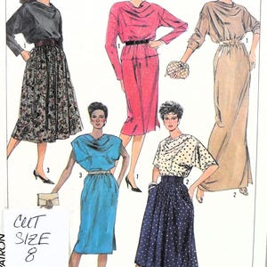 Puede incluir: Un sobre de patrón de costura con ilustraciones de cinco conjuntos con cuello tipo cowl, incluyendo un top negro con falda floral, un vestido rosa, un vestido largo beige, un vestido azul y un top de lunares con falda azul marino de lunares. Texto: CUT SIZE 8.