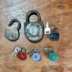 May include: A collection of seven vintage locks and keys. The locks are made of metal and have different colors, including red, blue, green, and black. The keys are silver and have different shapes. The locks are all closed and the keys are all separate from the locks.