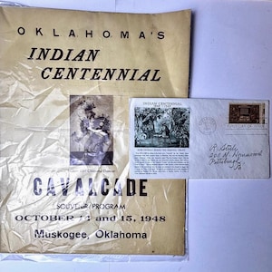 May include: A vintage souvenir program and envelope commemorating the Oklahoma Indian Centennial. The program, with text "Oklahoma's Indian Centennial Cavalcade," features a photo of a dancer and is dated October 14 and 15, 1948, in Muskogee, Oklahoma.