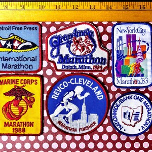 May include: Collection of vintage marathon patches. Patches include "Detroit Free Press International Marathon", "Grandma's Marathon Duluth, Minn. 1984", "New York City Marathon '83", "Marine Corps Marathon 1988", "Revco-Cleveland Marathon Finisher", and "Nationwide/Bank One Marathon".
