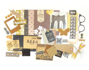 May include: A collection of scrapbook embellishments in shades of brown, gold, and white. Includes paper cutouts, tags, and stickers with text like "Sparkle," "Love Sweet Love," and "Hustle." Features a bicycle, birds, and a butterfly.