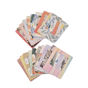 May include: A collection of square paper photo frames arranged in two fanned stacks. Each frame features a unique pattern, including floral prints, citrus slices, stripes, rainbows, and abstract shapes in various colors like pink, blue, and orange.