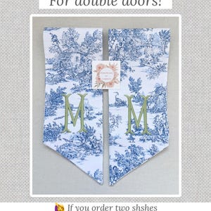 K&ouml;nnte beinhalten: Zwei passende T&uuml;rh&auml;nger mit blau-wei&szlig;em Toile-de-Jouy-Muster. Jeder H&auml;nger hat einen gr&uuml;n gestickten Buchstaben "M". Der Text "For double doors!" steht dar&uuml;ber. Der Shop-Name "PinkPeony by Christy" ist oben.