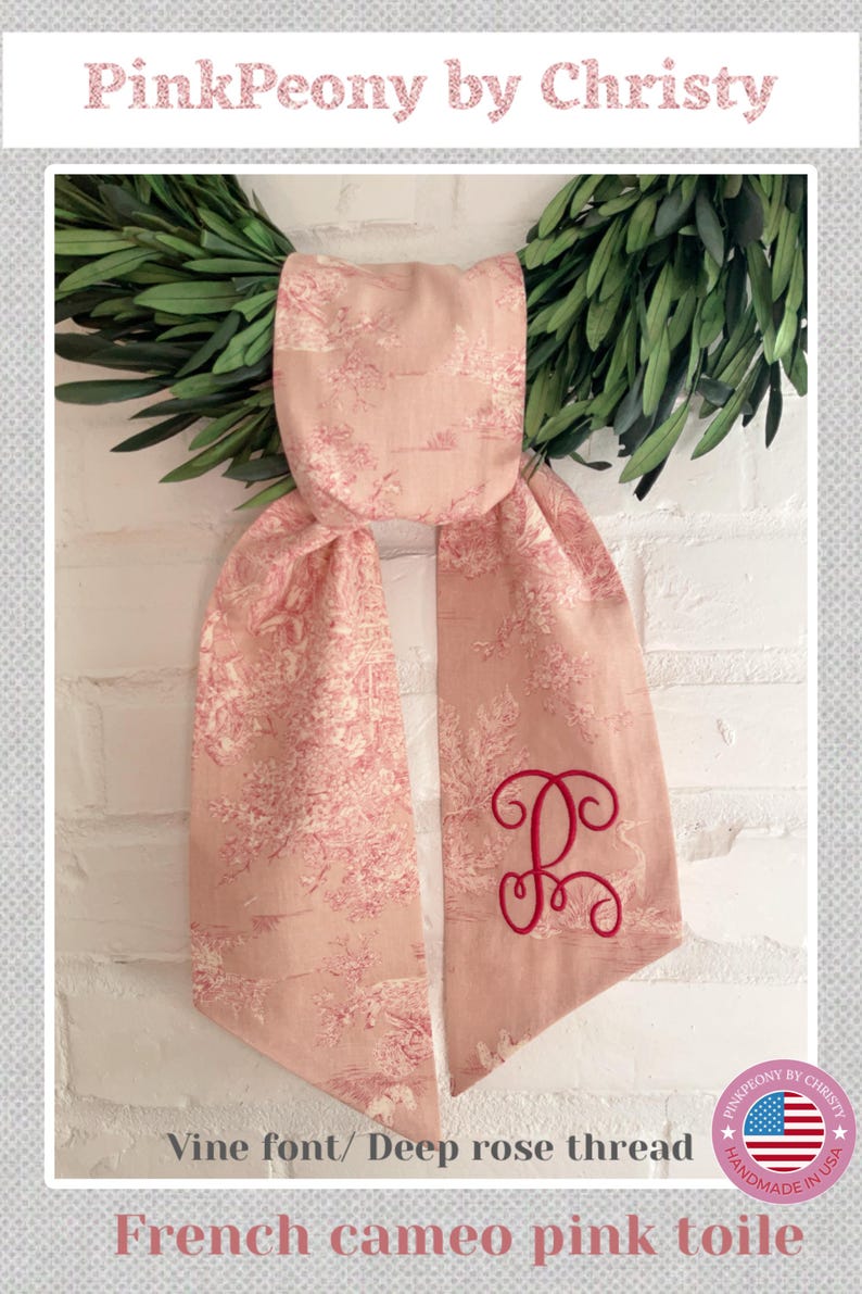 K&ouml;nnte beinhalten: Ein rosa Toile-Schal mit einem rot gestickten Initialen. Der Schal ist aus rosa Stoff mit franz&ouml;sischem Cameo-Design gefertigt. Der Text "PinkPeony by Christy" steht oben.