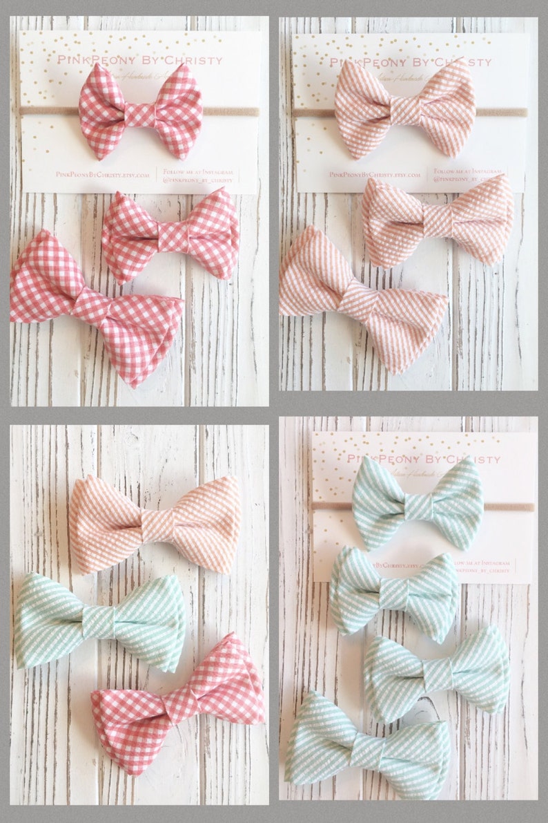 May include: Set of six gingham and striped fabric bow ties in pink, peach, and light blue. The bows are arranged in three pairs on a white wooden surface. The bows are handmade and are perfect for adding a touch of whimsy to any outfit.