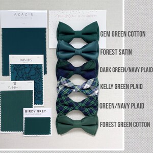 Pu&ograve; includere: Una selezione di papillon verdi, tra cui Gem Green Cotton, Forest Satin e motivi a quadri. Sono presenti anche campioni di tessuto di Azazie, David's Bridal e Birdy Grey. Il testo "PinkPeony by Christy" &egrave; visibile. Misure non applicabili.