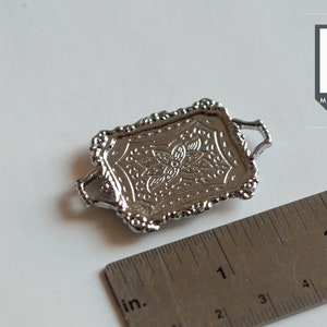 May include: Silver miniature serving tray with an ornate design and two handles. The tray measures approximately 1 inch in length.