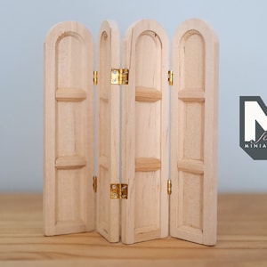 May include: A four-panel wooden room divider with arched tops and brass hinges. The divider is made of light wood and has a natural finish.