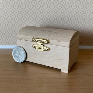 May include: A small wooden treasure chest with a gold latch and hinges. The chest is about the size of a UK 20 pence coin.
