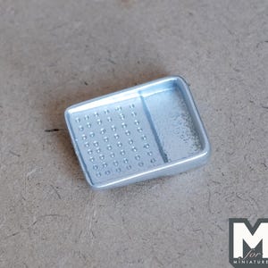 May include: A silver metal paint tray with a grid of small indentations. The tray is designed for holding small amounts of paint for miniature painting.