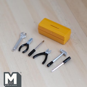 May include: A set of miniature tools, including a wrench, pliers, screwdriver, hammer, and a yellow toolbox. The tools are all silver and black with black handles.