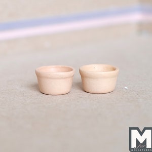 May include: Two small, pale peach-colored ceramic bowls. The bowls are round and have a slightly flared lip.