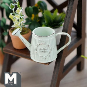 May include: A miniature white metal watering can with a distressed finish. The can has a handle and a spout and says "Healing Garden" on the side.