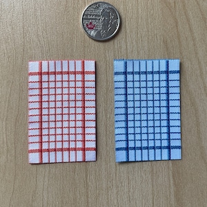 May include: Two kitchen towels, one red and white checkered and one blue and white checkered.