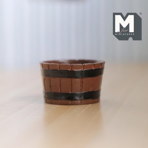 May include: A small brown wooden bucket with black painted bands. The bucket is made for miniature dollhouses.