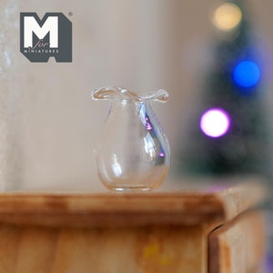 Op de afbeelding: Een kleine, heldere glazen vaas met een gerimpelde rand staat op een houten oppervlak. De vaas heeft een afgeronde body en een golvende bovenkant. Het logo "M for MINIATURES" is zichtbaar. Een vage kerstboom staat op de achtergrond.