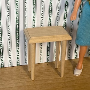 May include: A small wooden table with a light brown top and four legs. The table is sitting on a wood floor in front of a white and green striped wallpaper.
