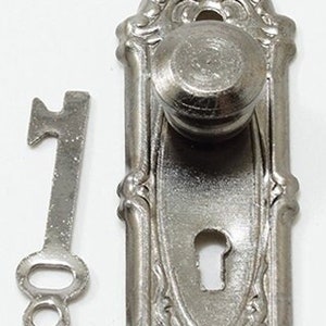 May include: A silver door knob with a keyhole and a decorative design. The knob has a round handle and a key is included.