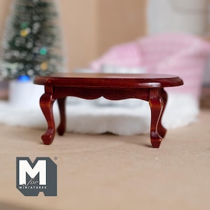 May include: A miniature wooden coffee table with a dark brown finish and an oval top. The table has four legs with a curved design.