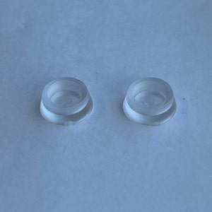 May include: Two clear plastic furniture pads with a raised lip around the edge. The pads are designed to protect floors from scratches.