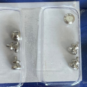 May include: A close-up of a clear plastic package containing six silver metal watch case backs. The case backs are in various shapes and sizes.