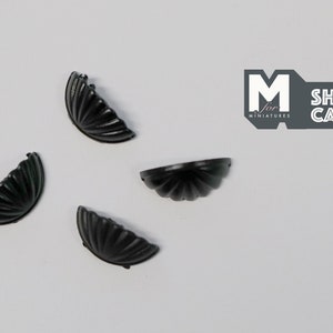May include: Four black metal shell-shaped drawer pulls. The pulls are approximately 3.8 cm in diameter.