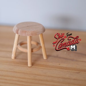 May include: A small wooden stool with a round seat and three legs. The stool is made of natural wood and has a simple design.
