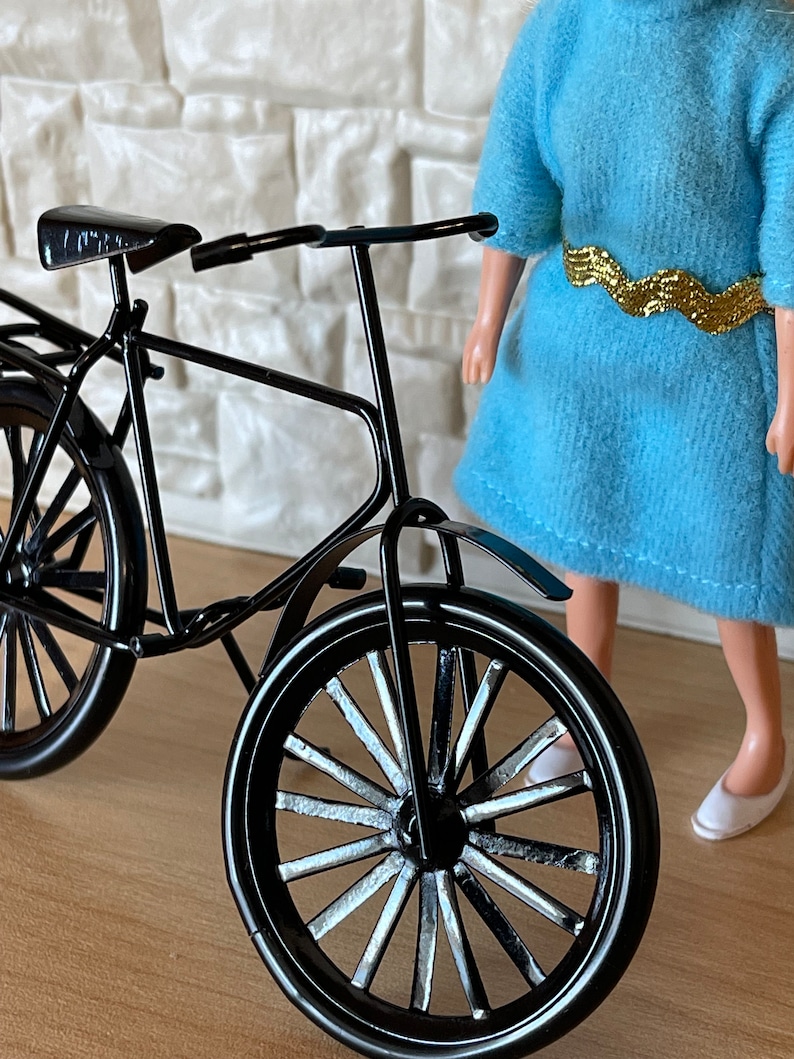 May include: A black metal bicycle with a white spoke wheel and a black seat. The bicycle is on a wooden surface.