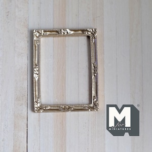 May include: A gold-colored picture frame with an ornate design. The frame is empty and ready to display a photo or artwork.