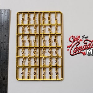 以下が含まれることがあります： モデル製作用の個別の文字と数字がついた金色のプラスチック製のランナー。文字はAからZ、数字は0から9です。