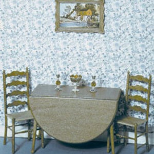 May include: A round wooden table with two chairs and a centrepiece. The table is set with two candlesticks and a bowl of fruit. The table is against a blue and white floral wallpaper with a framed picture above it.