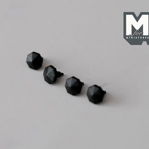 May include: Four black metal furniture knobs with a hexagonal shape and a pointed tip.