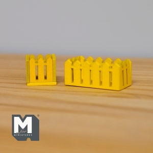 May include: Two miniature yellow picket fences, one tall and narrow, the other short and wide. The fences are made of wood and have a rustic look.