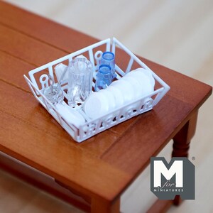 Pode incluir: Um escorredor de pratos de plástico branco com copos de plástico azul e pratos de plástico branco. O escorredor de pratos está sobre uma mesa de madeira.