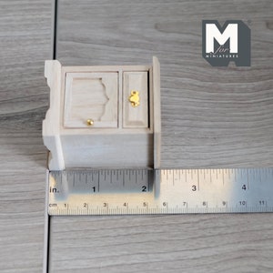 Peut inclure: Un petit cabinet en bois miniature avec une seule porte et un tiroir. Le cabinet mesure 5 cm de large et est en bois brut.