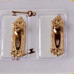 Può includere: Due set di maniglie per porte in miniatura color oro con dettagli ornati, ciascuno con una serratura e una piccola chiave. Le maniglie sono in una confezione di plastica trasparente, ideali per case delle bambole o progetti artigianali.