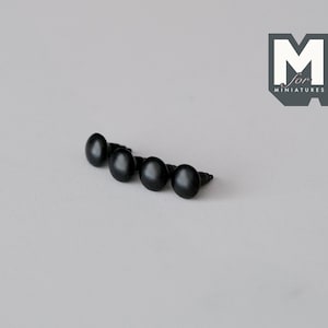 May include: Four black plastic eyes for miniature figures. The eyes are round and have a small screw on the back.